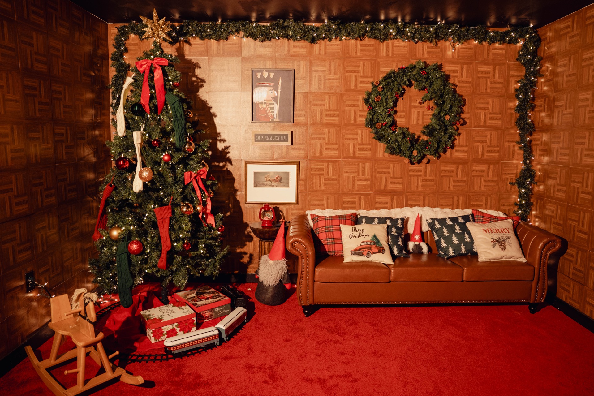 Christmas set with wood-paneled walls, a leather sofa, and decorated tree